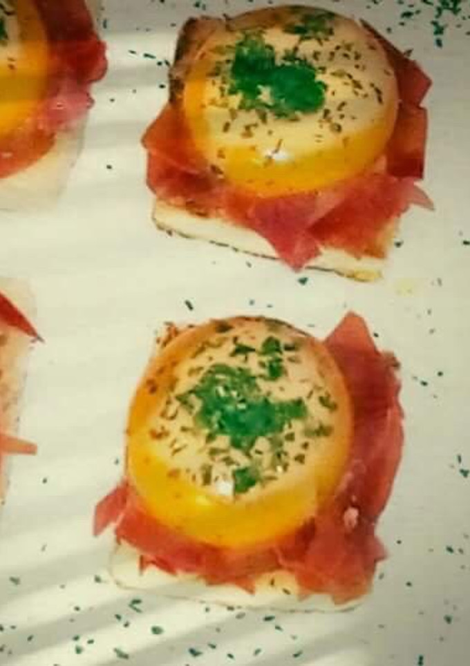 Una foto de Yemas de huevos rellenas de crema de tomate sobre un lecho de jamón ibérico