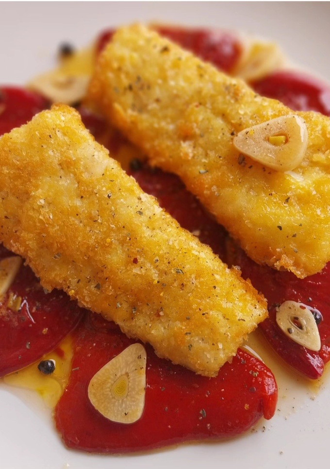 Una foto de Bacalao rebozado en copos de patata con piquillos confitados