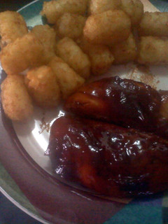 A picture of barbecue chicken with potatoes puffs.