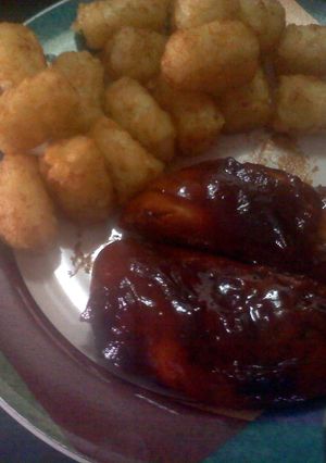 A picture of barbecue chicken with potatoes puffs.