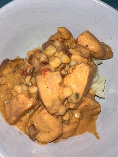A picture of Queso chicken with corn and side of rice.
