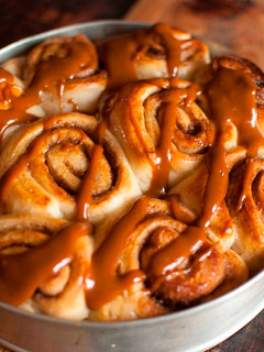 A picture of Cinnamon buns drizzled with warm caramel sauce.