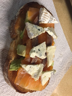 Una foto de Tostada de aguacate con salmón, anchoas y queso brie