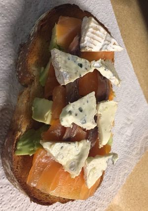 Una foto de Tostada de aguacate con salmón, anchoas y queso brie