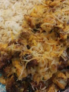 A picture of Teriyaki rice with bratwurst, potato, and scrambled eggs.