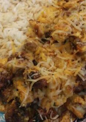 A picture of Teriyaki rice with bratwurst, potato, and scrambled eggs.