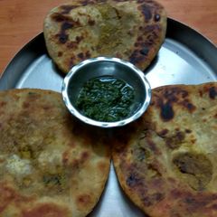 A picture of Achari Gobi ke parathe with green chutney.