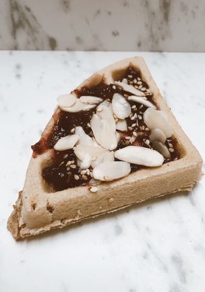 Una foto de Waffle de yuca con mermelada de frutos rojos y almendras fileteadas