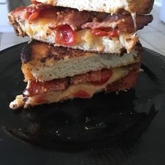 A picture of Luxe grilled cheese with tomatoes and bacon on Sourdough.