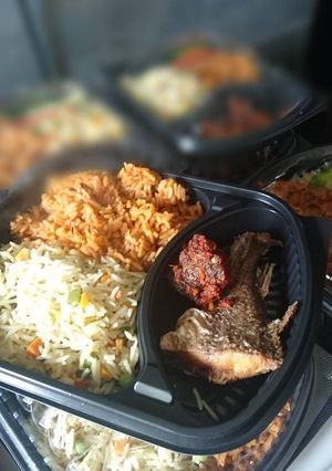 A picture of Fried and jollof rice with fried fish and meat.