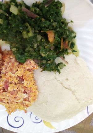 A picture of Ugali served with srambled egg and some vegetables.