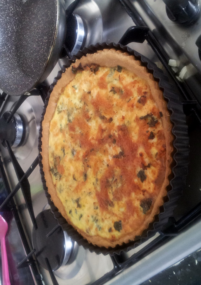 A picture of salmon, spinach and onion quiche.