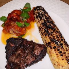 A picture of Grilled Fillet Mignon with grilled corn and roasted garlic tomatoes 🍅.