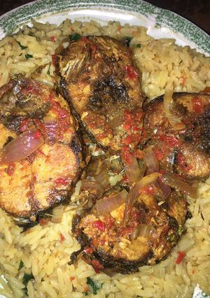 A picture of Local jellof rice with peppered fish.