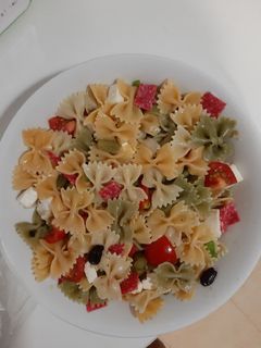 Una foto de Ensalada de pasta con queso feta, salami y tomates
