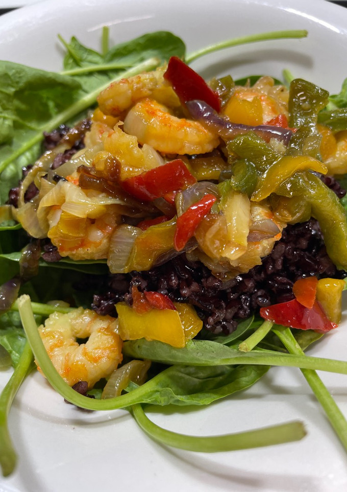Una foto de Ensalada templada de arroz negro venere con espinacas y gambas