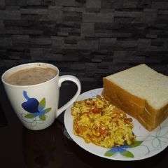 A picture of Scrambled eggs, bread and hot beverage.