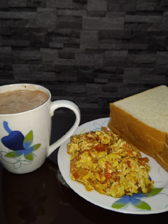 A picture of Scrambled eggs, bread and hot beverage.