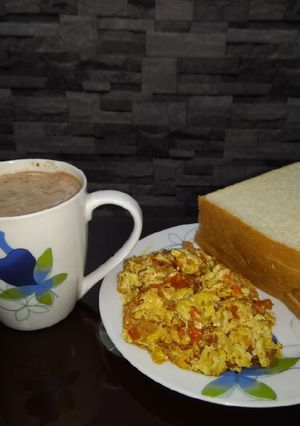 A picture of Scrambled eggs, bread and hot beverage.