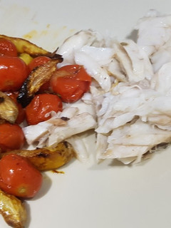 Una foto de Lubina al horno con tomates cherry, patatas y cebolla