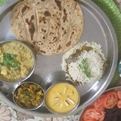 A picture of Biryani,Fried Gobhi,Aamras with laccha Parathha.