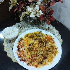 A picture of Mutton biryani with boondi and onion cucumber raita.