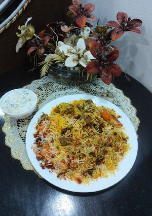 A picture of Mutton biryani with boondi and onion cucumber raita.