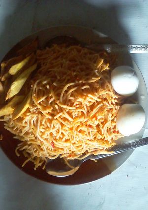 A picture of Spaghetti with fried plantain and boiled egg.