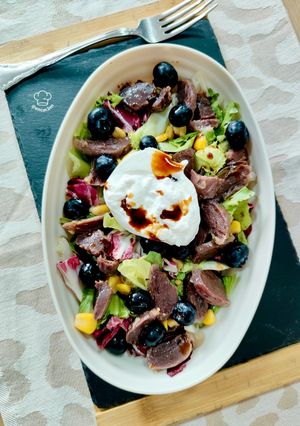 Una foto de Ensalada de mollejas de pato con arándanos y burrata trufada