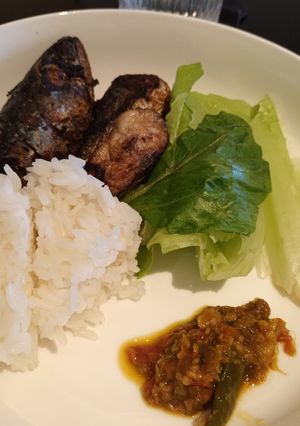 A picture of Mackerel fish, White rice, sambal and green lettuce.