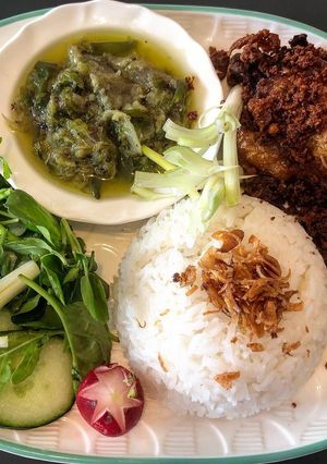 A picture of Indonesian deep fried duck with green chili sambal and crunchy bits.
