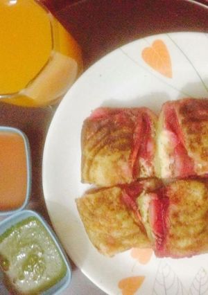 A picture of Bombai style cheese veg sandwich with fresh orange juice.