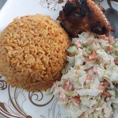 A picture of Jollof rice with coleslaw and fried chicken.