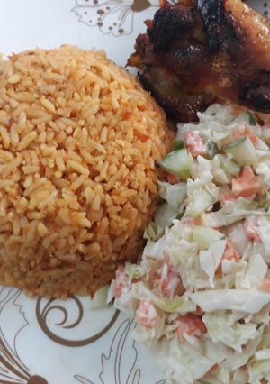 A picture of Jollof rice with coleslaw and fried chicken.