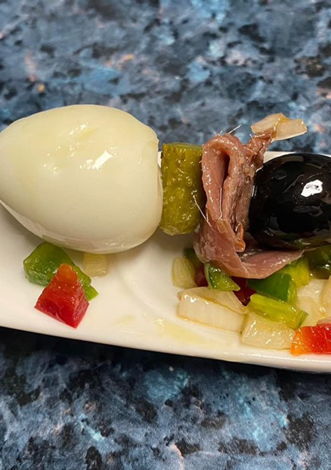 Una foto de Pincho de anchoa, huevo de codorniz y encurtidos con vinagreta de pimientos