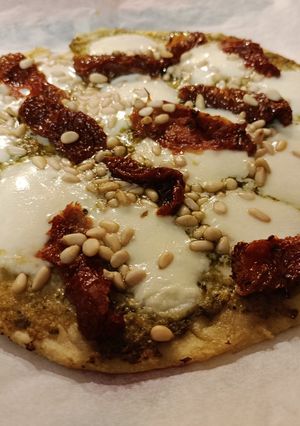 Una foto de Pizza de pesto, tomate seco y piñones