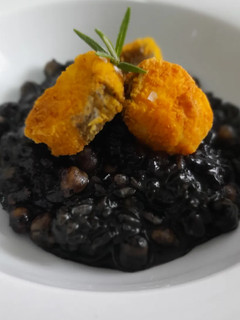 Una foto de Arroz negro meloso con garbanzos y merluza rebozada