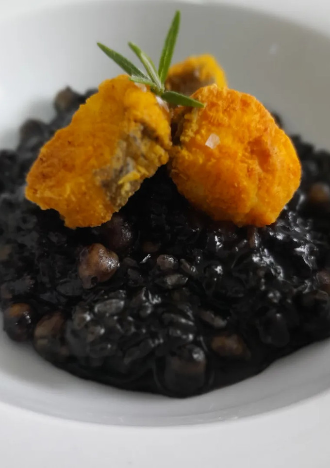 Una foto de Arroz negro meloso con garbanzos y merluza rebozada