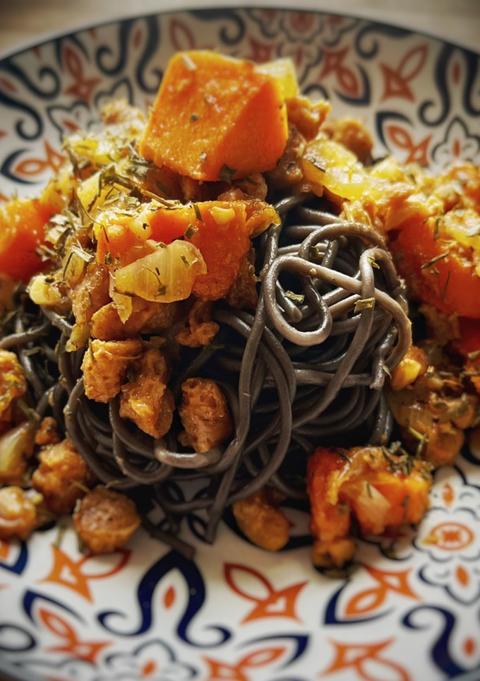 Una foto de Spaghetti nero di seppia con salsa picante de calabaza y soja texturizada