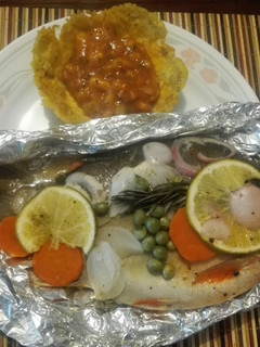 Una foto de Cachamas en sus jugos con verduras y naranja acompañada de ceviche de mango en canastilla de plátano