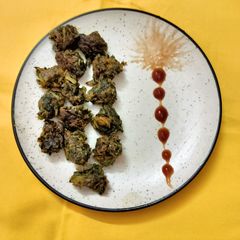 A picture of Coriander leaves pakoda with tomato sauce.