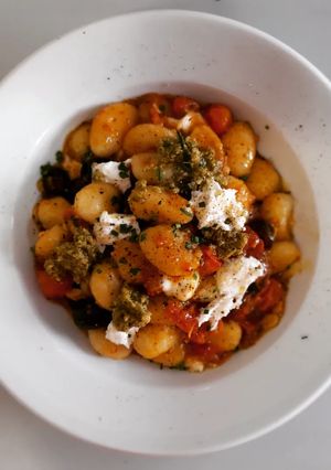 Una foto de Gnocchis picante al pesto con cherrys, olivas negras y mozzarella