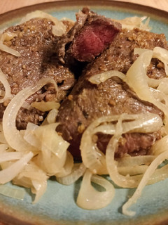 A picture of Steak with onions.