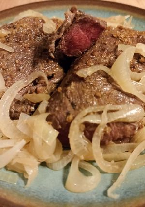 A picture of Steak with onions.