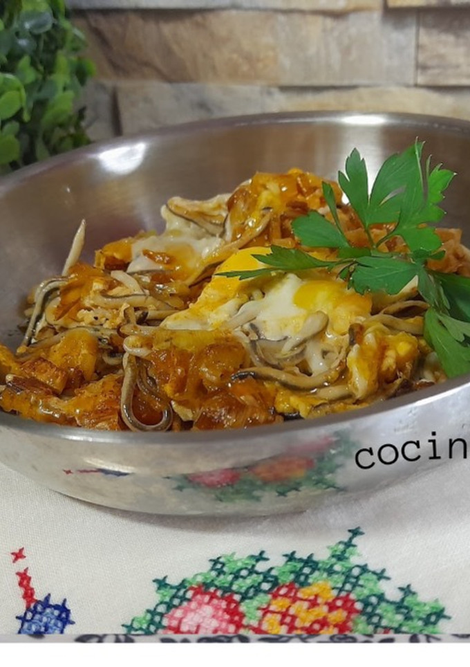 Una foto de Huevos rotos con gulas y puerro