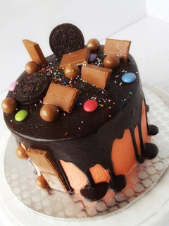 A picture of Vanilla sponge cake in chocolate drips with assorted toppers.