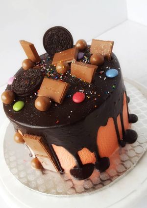 A picture of Vanilla sponge cake in chocolate drips with assorted toppers.