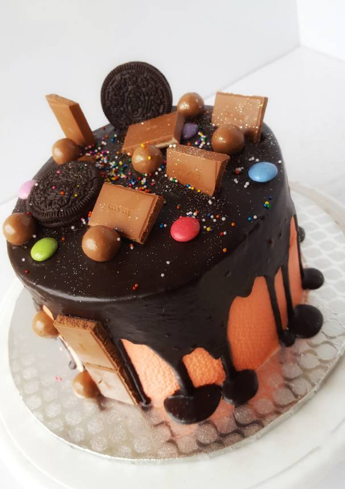 A picture of Vanilla sponge cake in chocolate drips with assorted toppers.