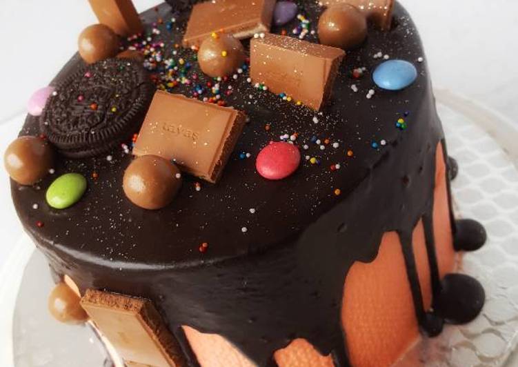 Vanilla sponge cake in chocolate drips with assorted toppers