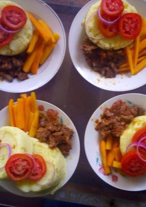 A picture of Mashed potatoes,brown lamb stew and buttered carrot.